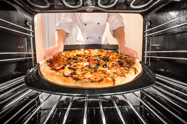 Lo chef prepara la pizza al forno, vista dall'interno del forno. Cottura al forno.