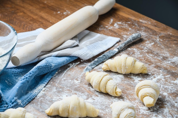 Lo chef prepara manualmente i croissant sul tavolo con gli ingredienti.