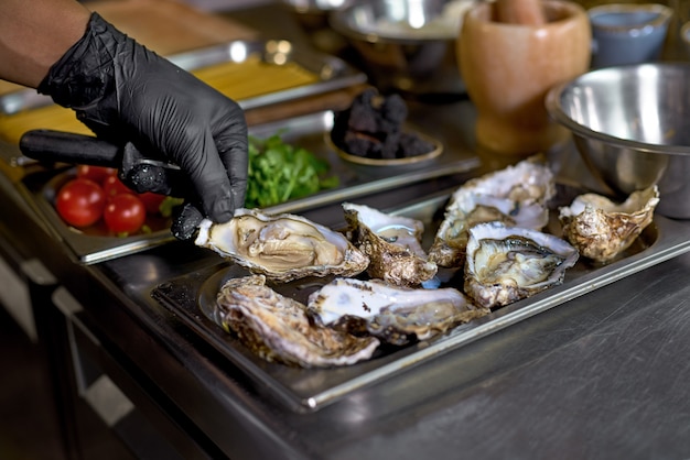 Lo chef prepara ostriche per un piatto su un tavolo in cucina,