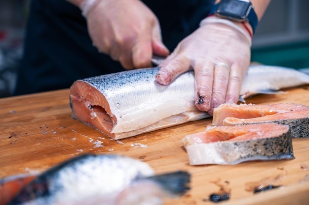 Lo chef prepara un salmone sbudellandolo e sfilettandolo in cucina