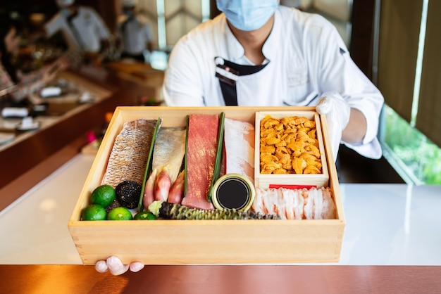 Lo chef presenta gli ingredienti freschi in una scatola di legno prima di preparare il pasto Omakase.