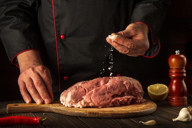 Lo chef professionista cosparge di sale la carne cruda