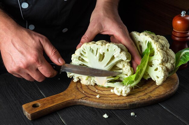 Lo chef professionista sta tagliando il cavolfiore nella cucina del ristorante