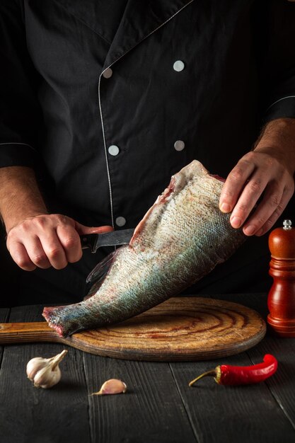 Lo chef professionista taglia il pesce prima della cottura Ambiente di lavoro nella cucina del ristorante