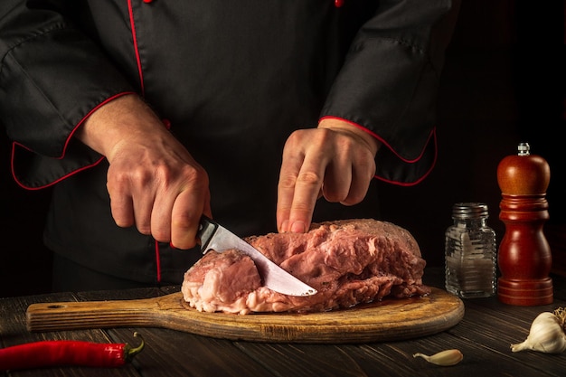 Lo chef professionista taglia la carne con un coltello prima della cottura