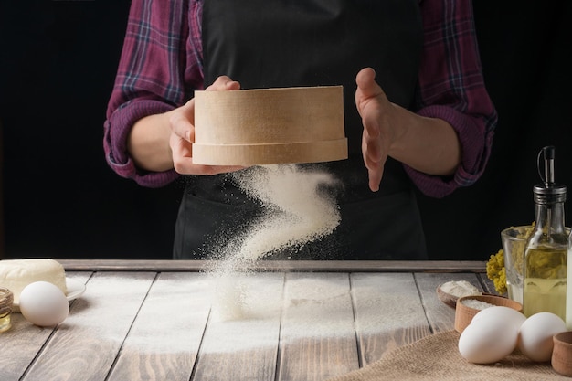 Lo chef spolvera la farina sulla superficie Sfondo nero