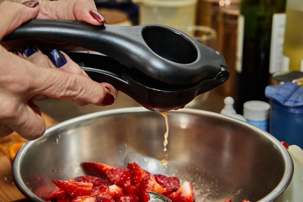 Lo chef spreme il succo d'arancia in fragole a fette per dessert nella cucina di casa