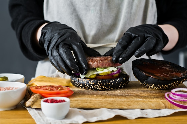 Lo chef sta cucinando un cheeseburger. Il concetto di cucinare un hamburger nero. Ricetta hamburger fatta in casa.