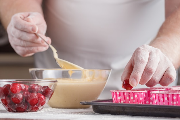 Lo chef sta decorando deliziosi muffin biologici. torte di ciliegie in ambiente naturale.