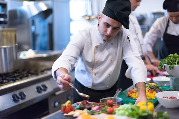 Lo chef sta finendo il piatto di carne di bistecca con infine il condimento del piatto e quasi pronto per essere servito al tavolo