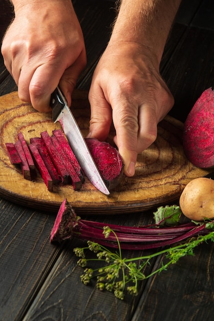 Lo chef taglia barbabietole o beta vulgaris con un coltello per preparare un delizioso borscht