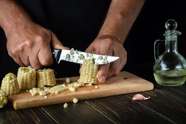 Lo chef taglia i chicchi di mais bolliti con un coltello