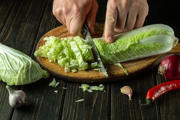 Lo chef taglia il cavolo fresco con un coltello Cucinare insalata di verdure nella cucina del ristorante