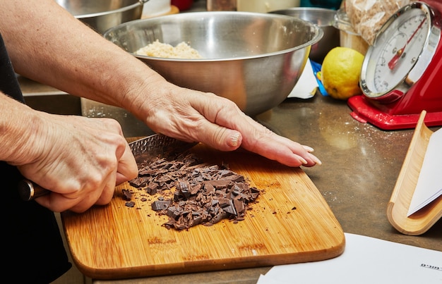 Lo chef taglia il cioccolato con il coltello per fare la torta al cioccolato.