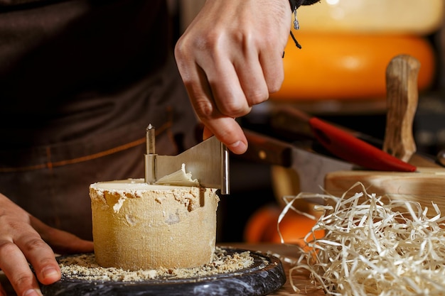 lo chef taglia il formaggio di capra con uno speciale coltello da formaggio il concetto di produzione e vendita di