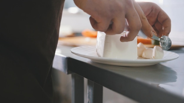 Lo chef taglia il formaggio in cucina commerciale, primo piano