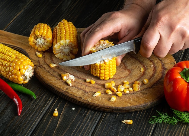 Lo chef taglia il mais con un coltello Il mais è un'ottima colazione o pranzo dietetico