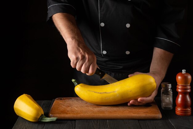 Lo chef taglia il midollo giallo maturo con un coltello. Le zucchine fritte sono un'ottima dieta per colazione o pranzo. Ambiente di lavoro sul tavolo della cucina del ristorante. Spazio pubblicitario gratuito.