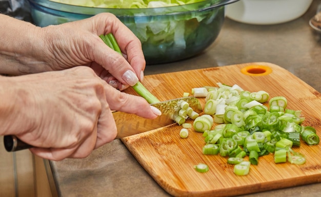 Lo chef taglia il porro su tavola di legno in cucina