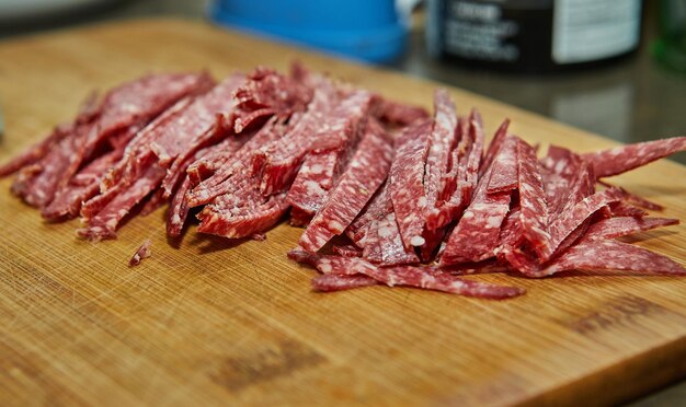 Lo chef taglia il salame su tavola di legno in cucina