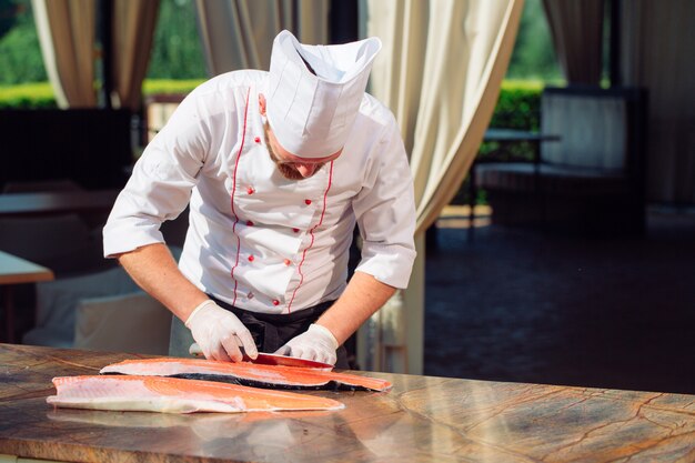 Lo chef taglia il salmone sul tavolo.