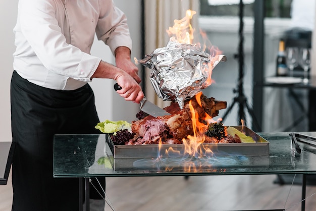 Lo chef taglia la Turchia al forno su un piatto nel fuoco. Tacchino arrosto.