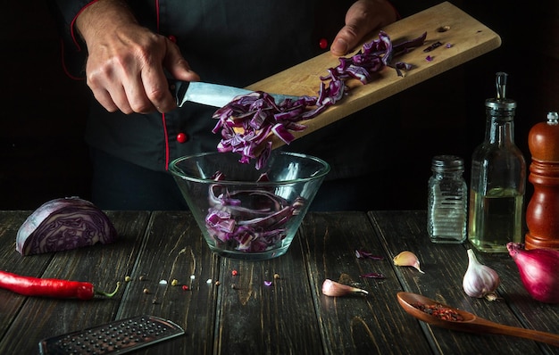 Lo chef versa il cavolo rosso nella ciotola Cucinare insalata di verdure nella cucina del ristorante