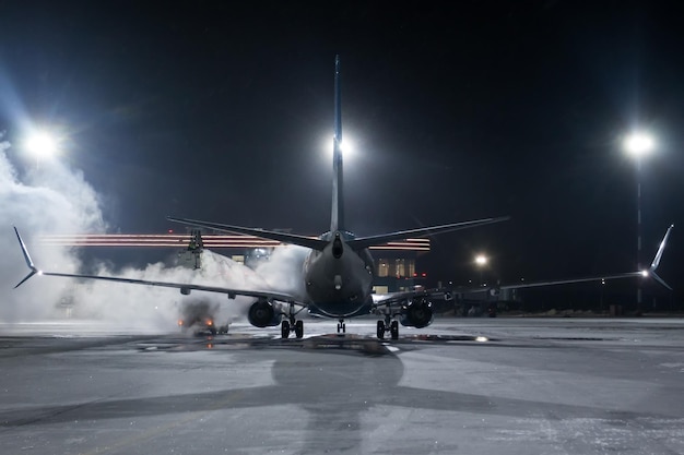 Lo sbrinamento a terra di un aereo di linea passeggeri sul piazzale dell'aeroporto di notte in inverno