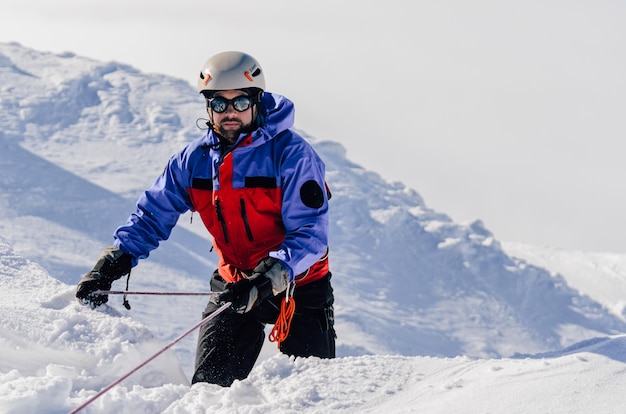 Lo scalatore è fissato su una corda su un pendio di montagna innevato