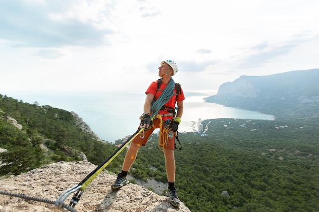 Lo scalatore scala la montagna su un cavo con vista sulla foresta e sul mare