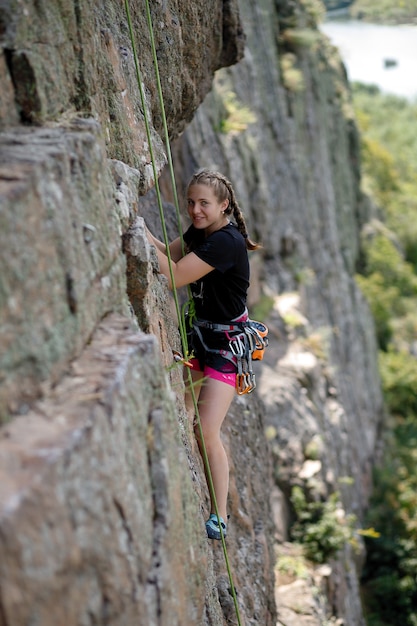 Lo scalatore supera il percorso di arrampicata impegnativo. Una ragazza si arrampica su una roccia. Donna impegnata in sport estremi. Passatempo estremo.