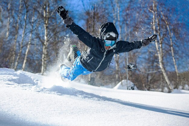 Lo sciatore uomo gioioso in una maschera salta nella neve a debole coesione e si rallegra in inverno