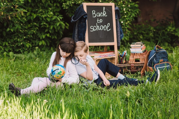 Lo scolaro e la scolara felici stanno osservando il globo