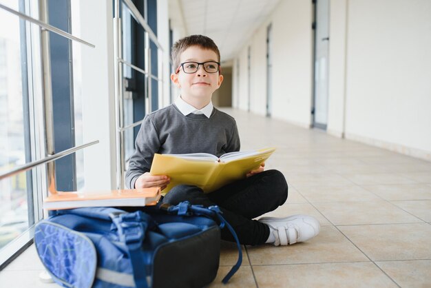 Lo scolaro si siede sul pavimento di un corridoio della scuola e legge un libro