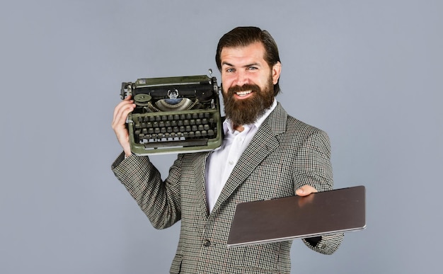 Lo scrittore di scelta giusta scrive con la macchina da scrivere e il laptop Uomo con la barba in giacca con la nuova tecnologia della macchina da scrivere retrò nella vita moderna Uomo che lavora su una macchina da scrivere retrò in libreria meccanica vs digitale