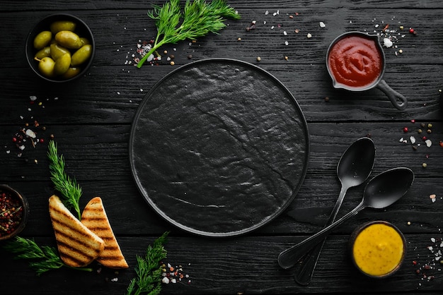 Lo sfondo della cucina Un insieme di spezie e verdure fresche Vista dall'alto Spazio libero per il testo Su uno sfondo di pietra nera