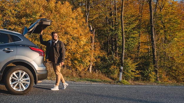 Lo sfondo della foresta autunnale con un uomo sorridente apre il suo spazio per la copia dell'auto