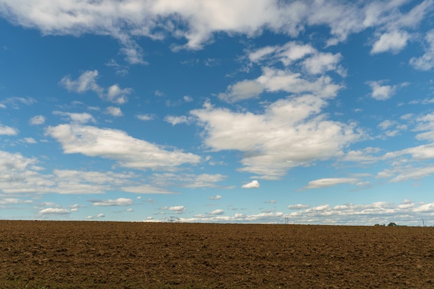 Lo sfondo è un campo arato e bellissime nuvole profondi solchi nel terreno dopo il lavoro del trattore con un arato Arare il terreno il trattamento del suolo superiore per saturare il suolo con ossigeno