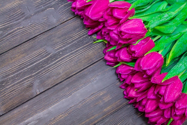 Lo spazio della copia del giorno delle donne con i tulipani rosa luminosi su un fondo di legno nero, strutture