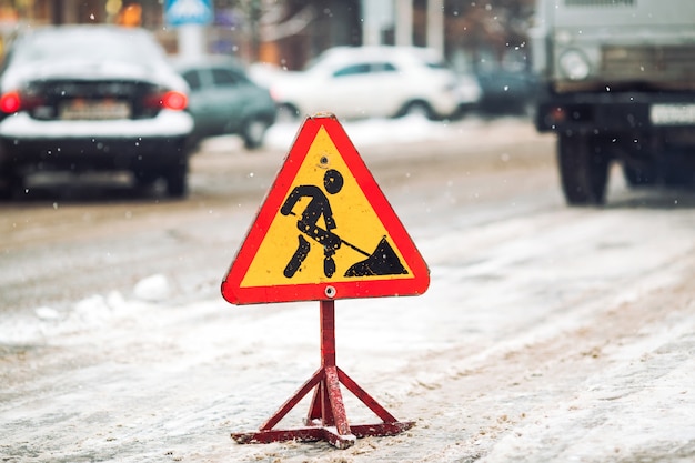 Lo spazzaneve rimuove la neve dalla via della città. Segnale stradale d'avvertimento.