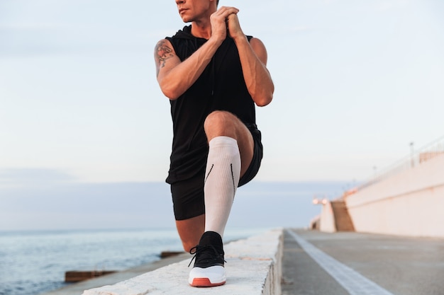 Lo sportivo all'aperto in spiaggia fa esercizi di stretching.