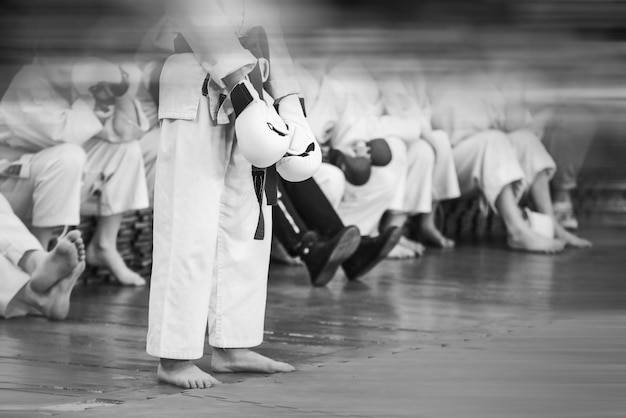 Lo sportivo karateka in un kimono bianco si sta preparando per un duello Stile vintage con rumore del film e sfocatura del movimento Focus sui guanti nelle mani