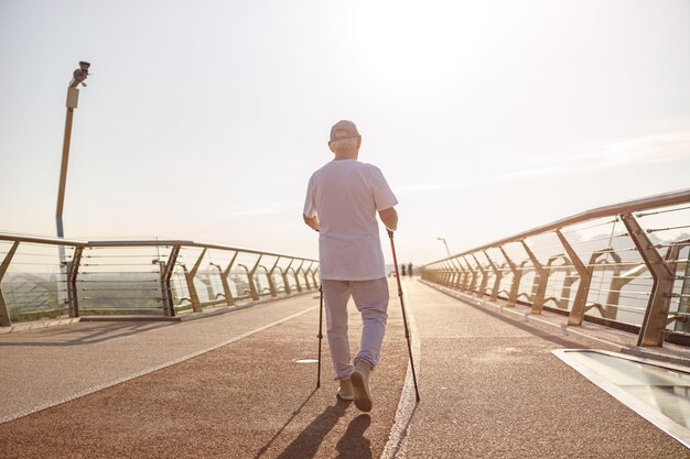 Lo sportivo maturo pratica il nordic walking su una passerella vuota