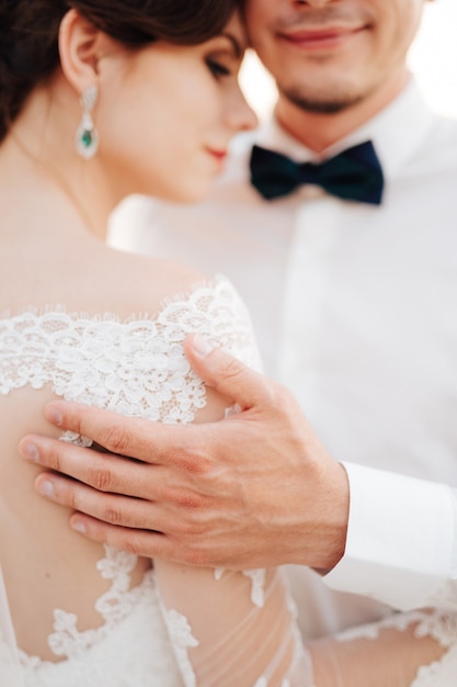 Lo sposo abbraccia dolcemente la sposa con la mano sulla sua spalla