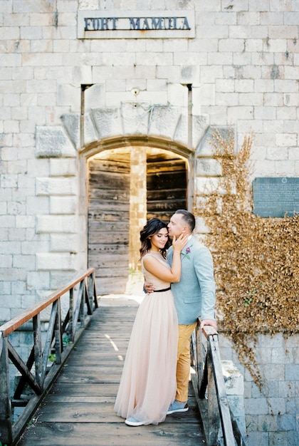 Lo sposo abbraccia e bacia la sposa sulla fronte sul ponte vicino al forte mamula