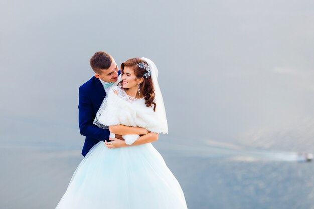 Lo sposo abbraccia e bacia la sposa sullo sfondo del fiume