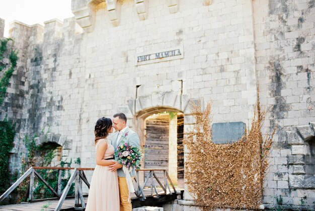 Lo sposo abbraccia la sposa vicino all'ingresso principale di Mamula Fort