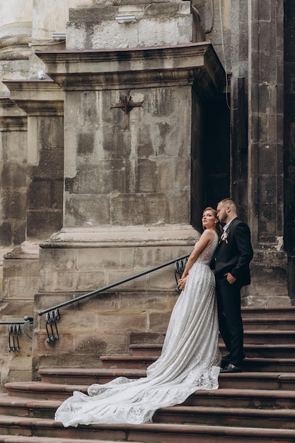 Lo sposo alla moda abbraccia da dietro la bella sposa