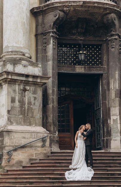 Lo sposo alla moda abbraccia da dietro la bella sposa