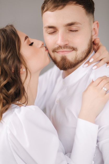 Lo sposo con la sua adorabile sposa si abbraccia e si bacia sulla guancia sposi felici di fronte a gray